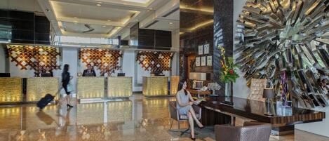 A modern lobby with a reception desk, seating area, and decorative wall art.