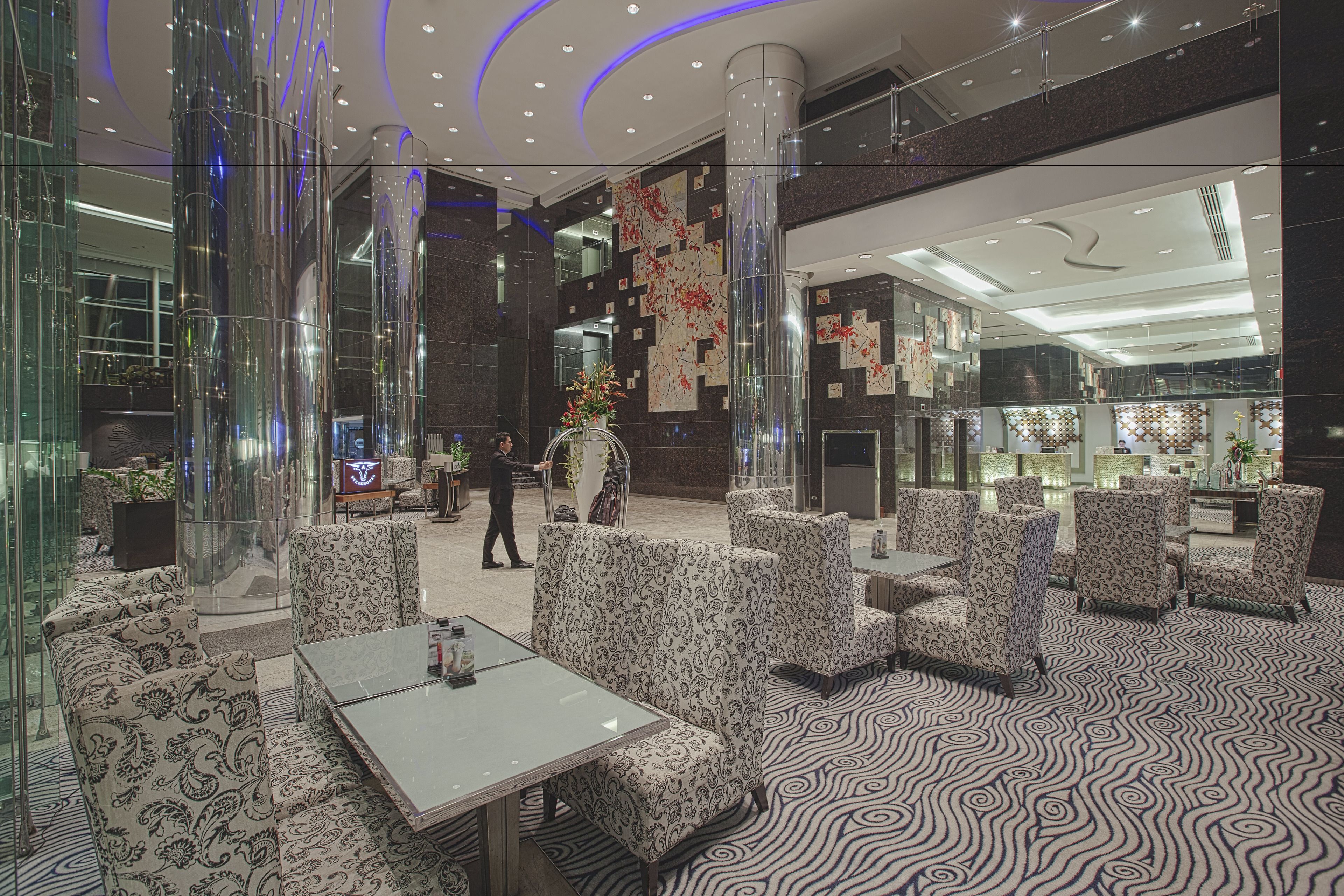Un hall d’entrée avec des canapés à motifs, une colonne en verre et une moquette à motifs.