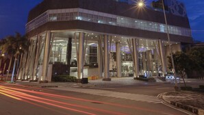 A multi-story hotel with a prominent 'ACAPO' sign, featuring a modern architectural design with a glass facade and a green accent on the lower levels. - Acacia Hotel Manila (Muntinlupa)