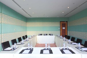 Un salón de conferencias con una larga mesa, sillas, botellas de agua y tarjetas de identificación.