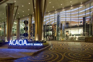 Exterior del hotel Acacia Manila, con un diseño moderno, que presenta una entrada destacada y un piso con diseño.