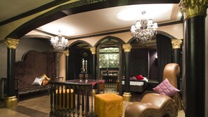 A luxurious room with a grand chandelier, ornate columns, and a plush armchair. - Victoria Court Hillcrest - Pasig (Pasig)