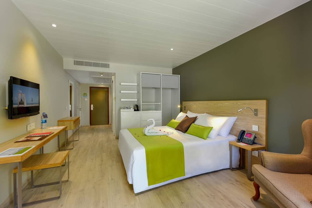 Een hotelkamer met een bed, een bureau, een stoel, een televisie en een telefoon.