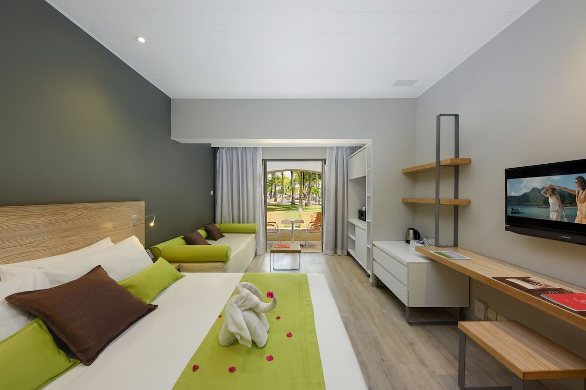 Een moderne hotelkamer met een bed, een bureau, een televisie en uitzicht op het omliggende landschap.