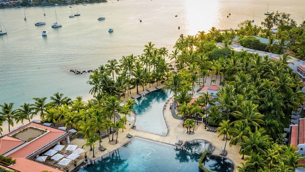 Ein Resort mit einem großen Pool, umgeben von Palmen, einem Strand und Booten im Wasser.