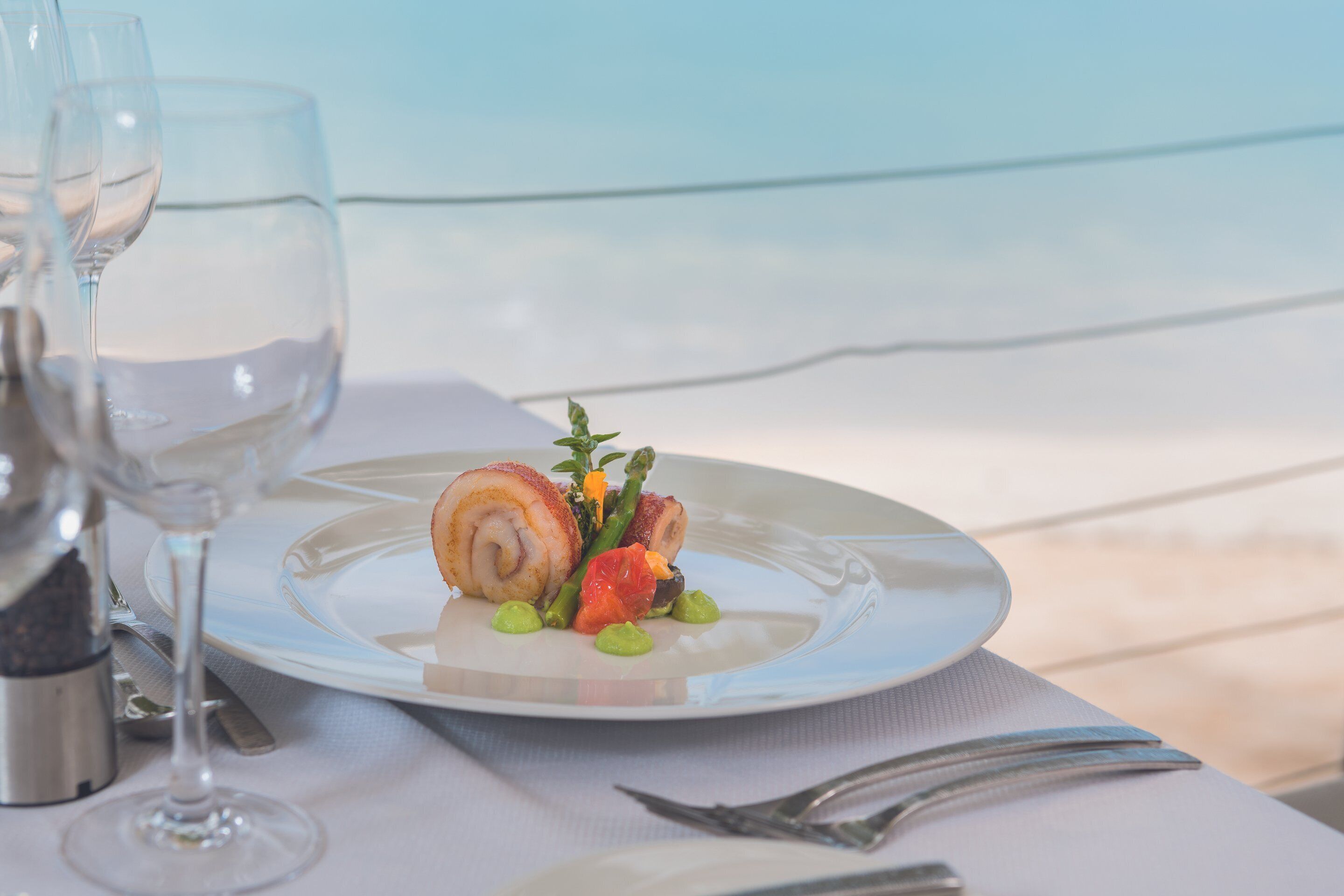 A table set with a plate of food, a glass of water, and a salt shaker.