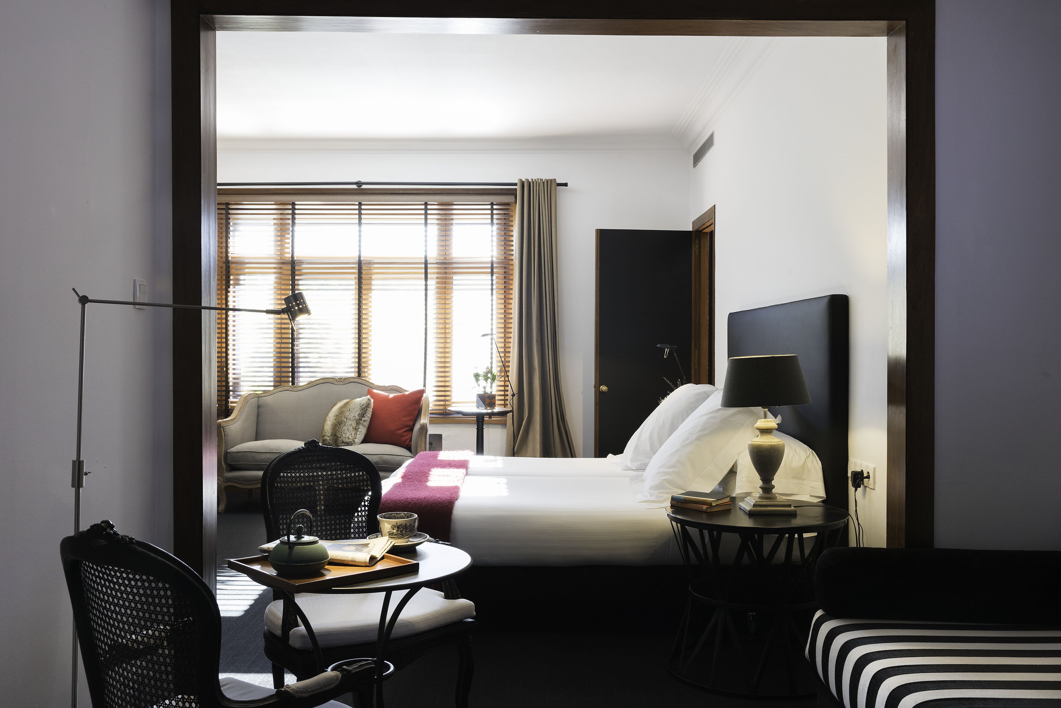Una habitación de hotel con una cama, un escritorio con lámpara, una silla y un sofá.