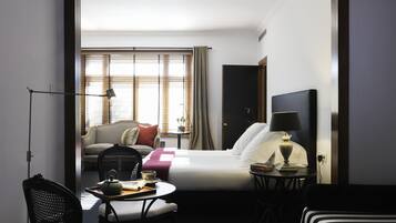 Una habitación de hotel con una cama, un escritorio con lámpara, una silla y un sofá.