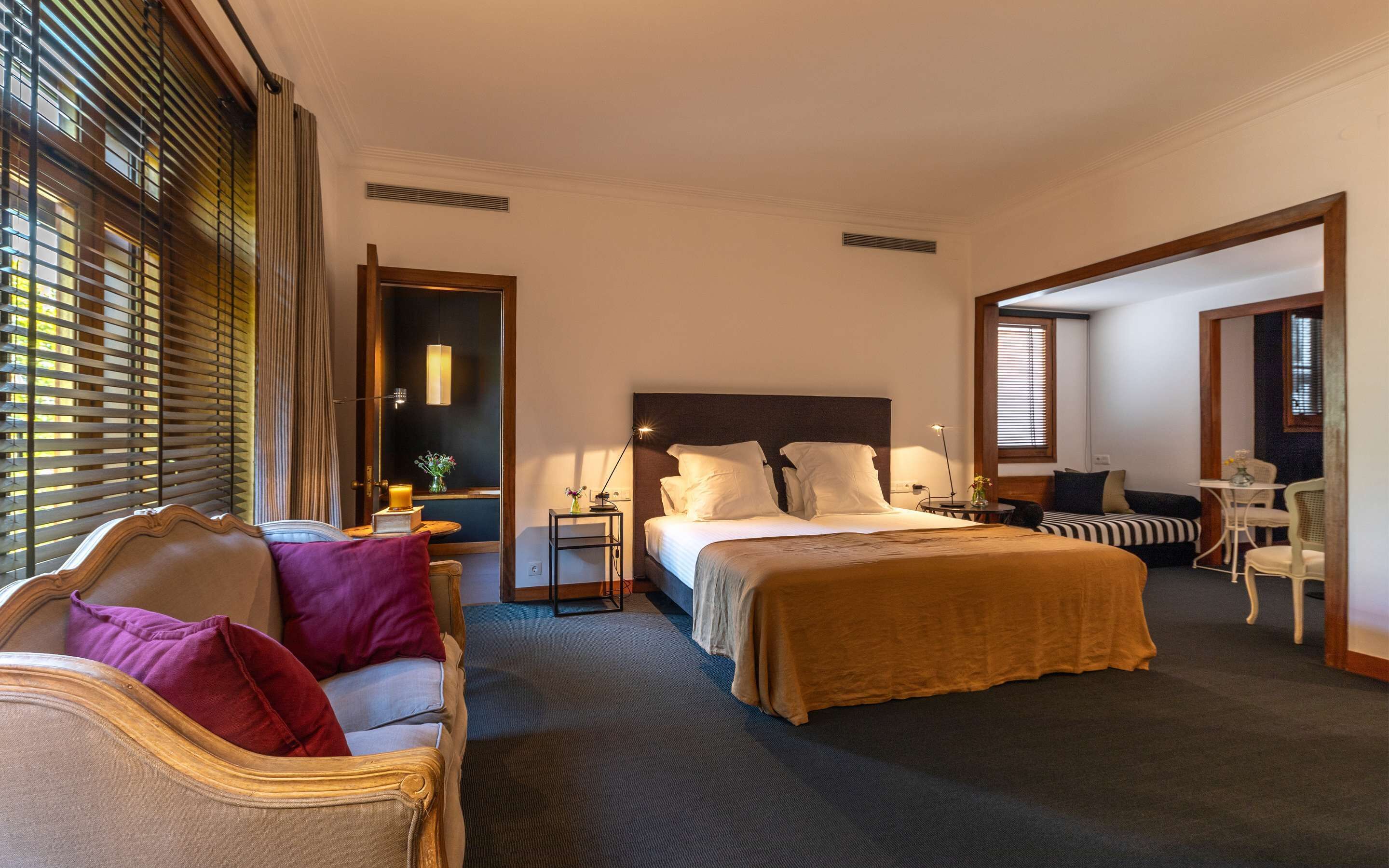 Una habitación de hotel con una cama grande, un sofá, una mesita y una silla.
