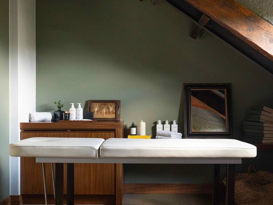 Una habitación con un banco de madera, un armario de madera y un cuadro en la pared.