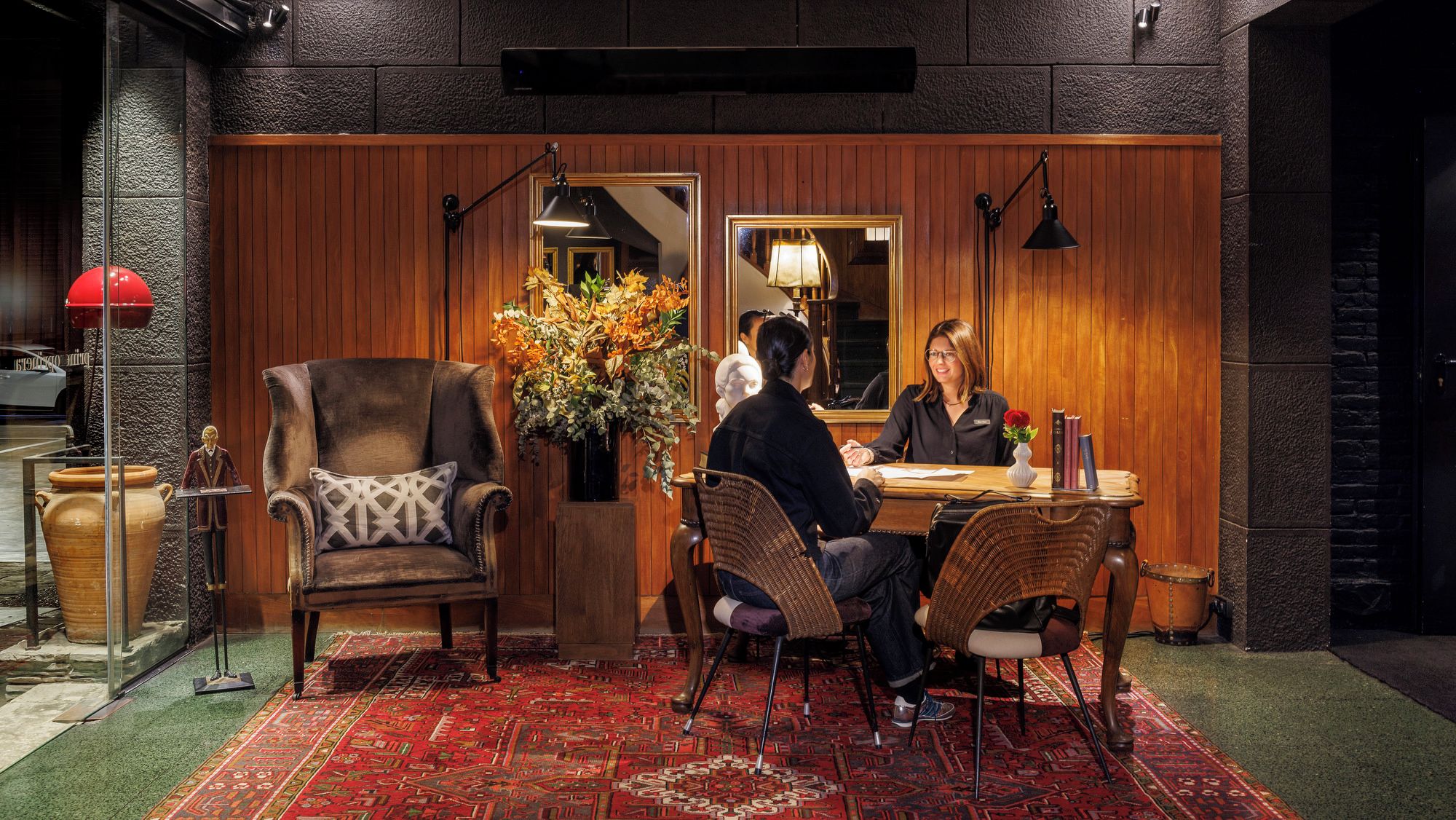 A cozy interior with a wooden-paneled wall, a dining table with chairs, and a large mirror.