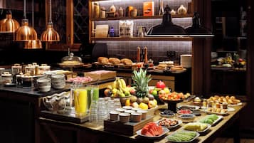 Un buffet con un'ampia scelta di cibi e bevande, tra cui frutta, pasticceria e salse.
