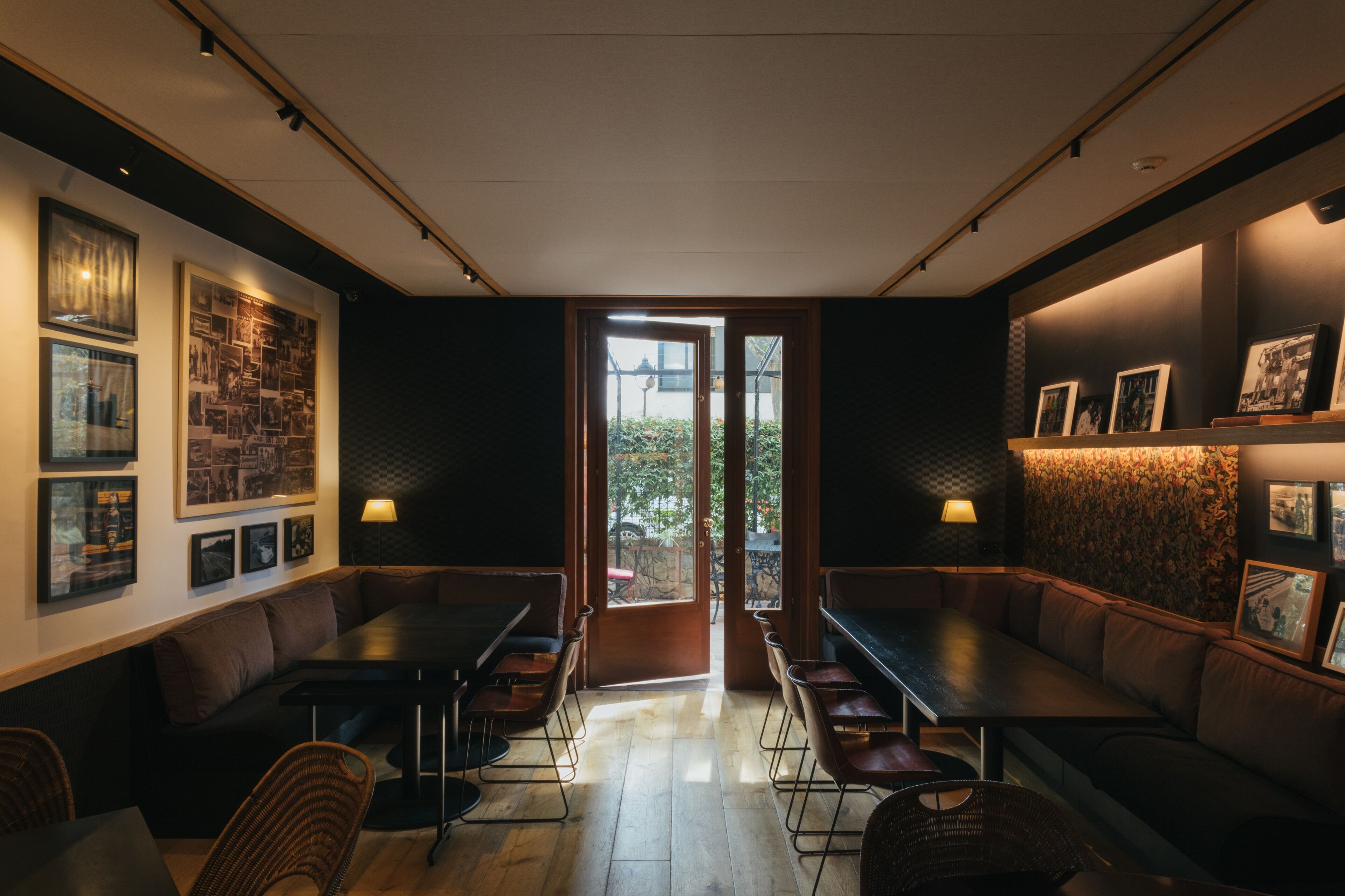 A modern interior with a central seating area, framed pictures on the walls, and a view through a glass door.