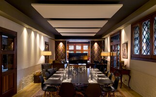 A conference room with a long table, chairs, and a large screen.