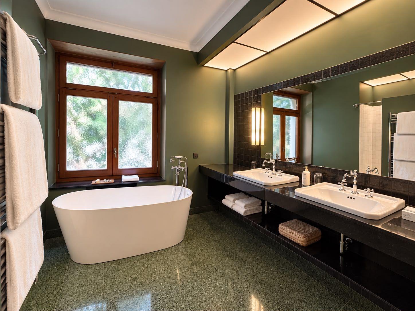 A modern bathroom with a freestanding bathtub, two sinks, and a large mirror.