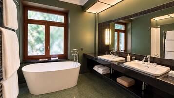 A modern bathroom with a freestanding bathtub, two sinks, and a large mirror.