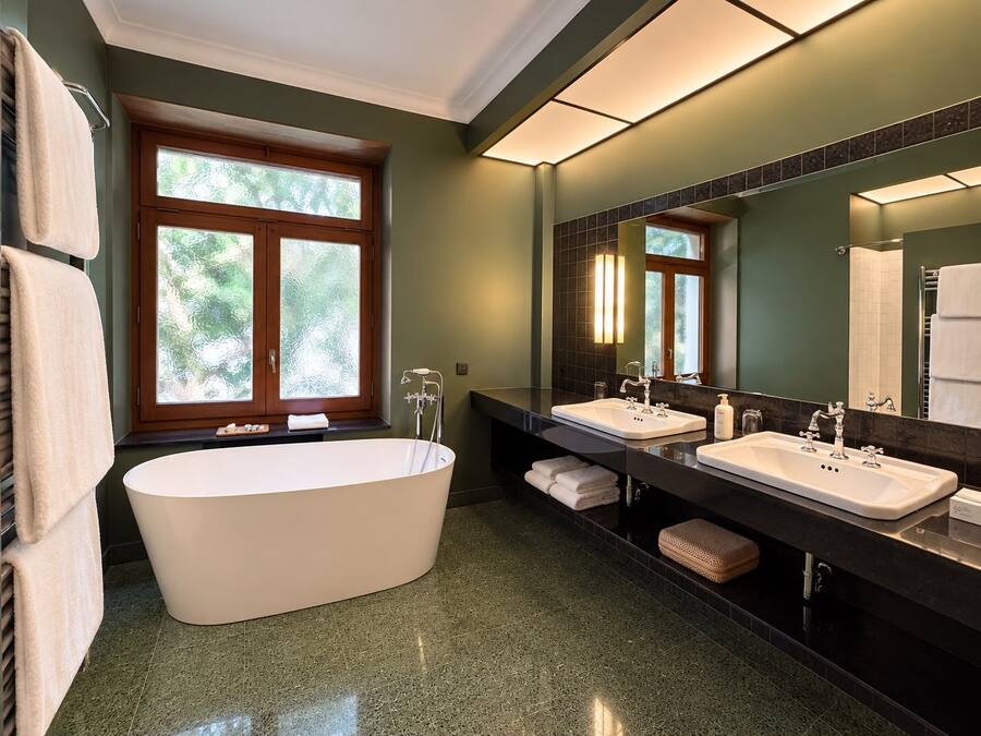 A modern bathroom with a freestanding bathtub, two sinks, and a large mirror.