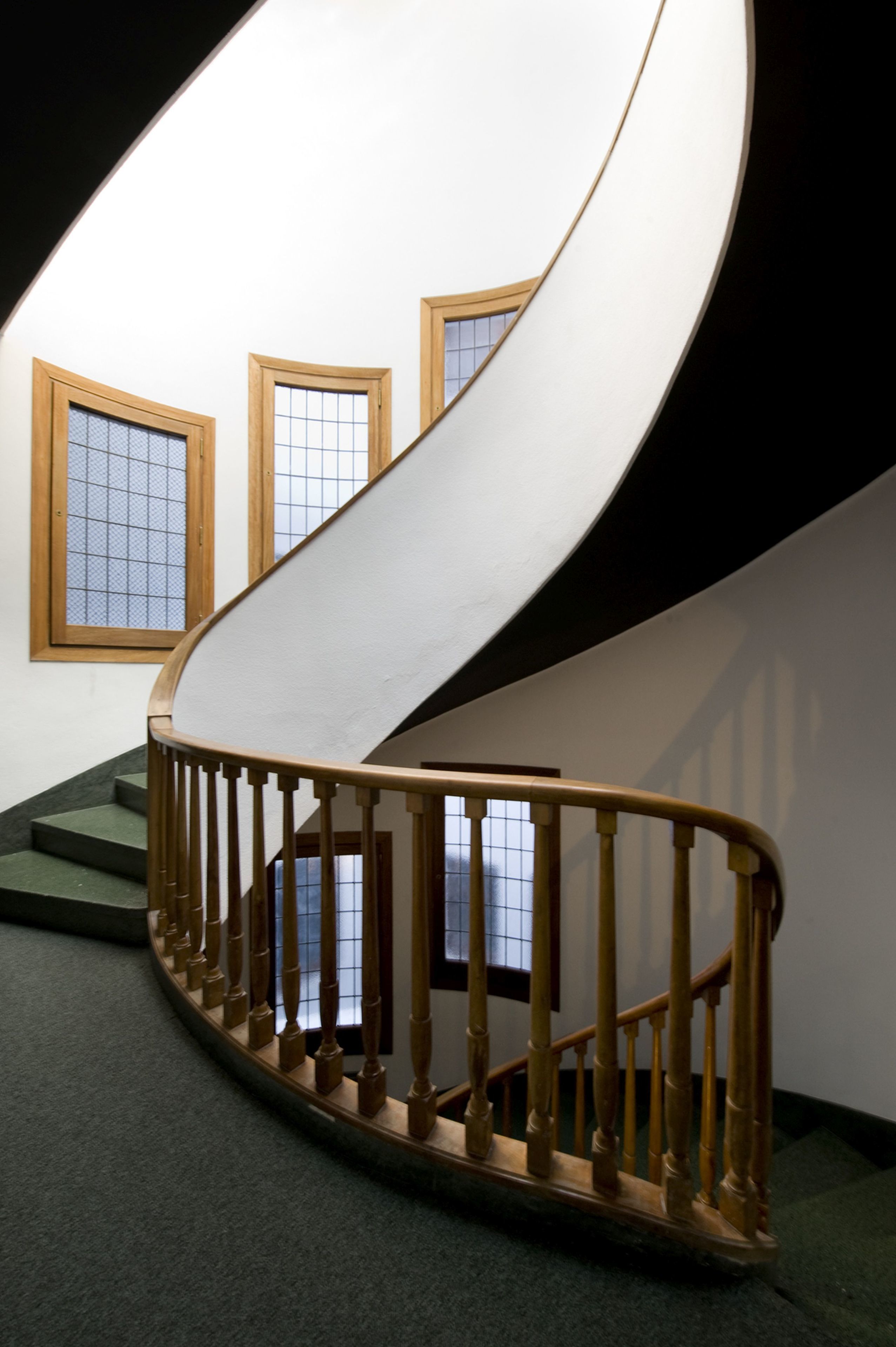 A spiral staircase with wooden balusters and a carpeted floor.