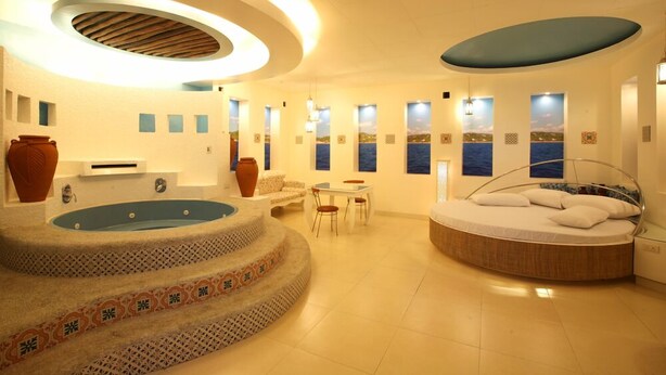 A modern bathroom with a circular jacuzzi, a round bed, and a dining area. - Victoria Court Malabon (Malabon)