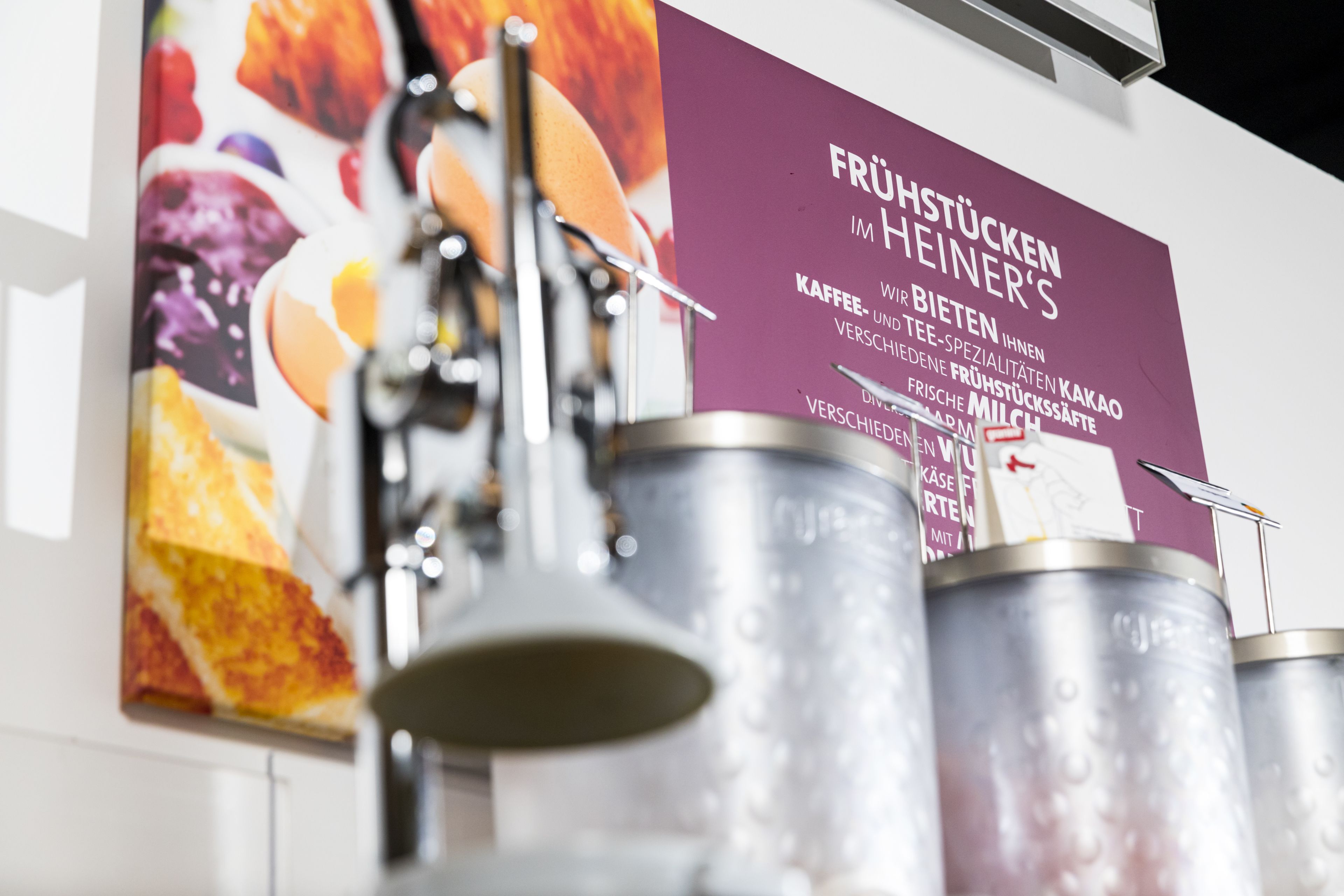 A coffee machine and several stainless steel containers on a wall.