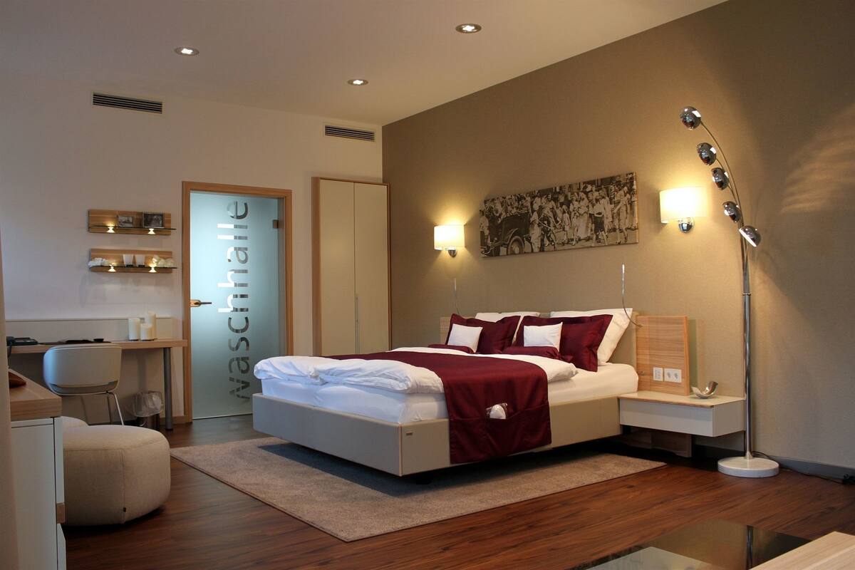 A modern bedroom with a large bed, bedside tables, a desk, and a floor lamp.