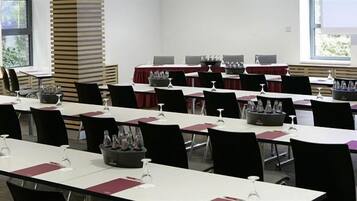 Un salón de conferencias con varias mesas y sillas dispuestas en filas.