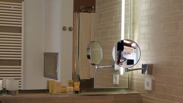 A modern bathroom with a large mirror, a sink, and a towel rack.