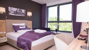 Una habitació d'hotel moderna amb un llit gran, un escriptori, una cadira i una banyera.