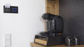 Een moderne keuken met een Bosch koffiezetapparaat, een houten ladeblok en twee zwarte mokken op een donker aanrecht.
