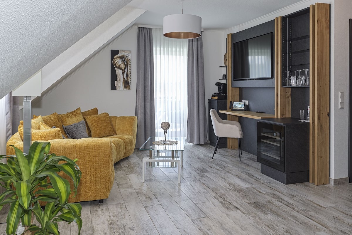 Un salon moderne avec un canapé, une table basse et un téléviseur fixé à un mur en bois.