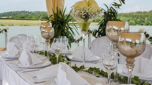 Una mesa dispuesta para un evento formal, con manteles blancos, cristalería transparente y un centro de mesa floral.