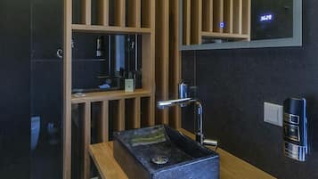 A modern bathroom with a wooden vanity, a black sink, and a mirror.