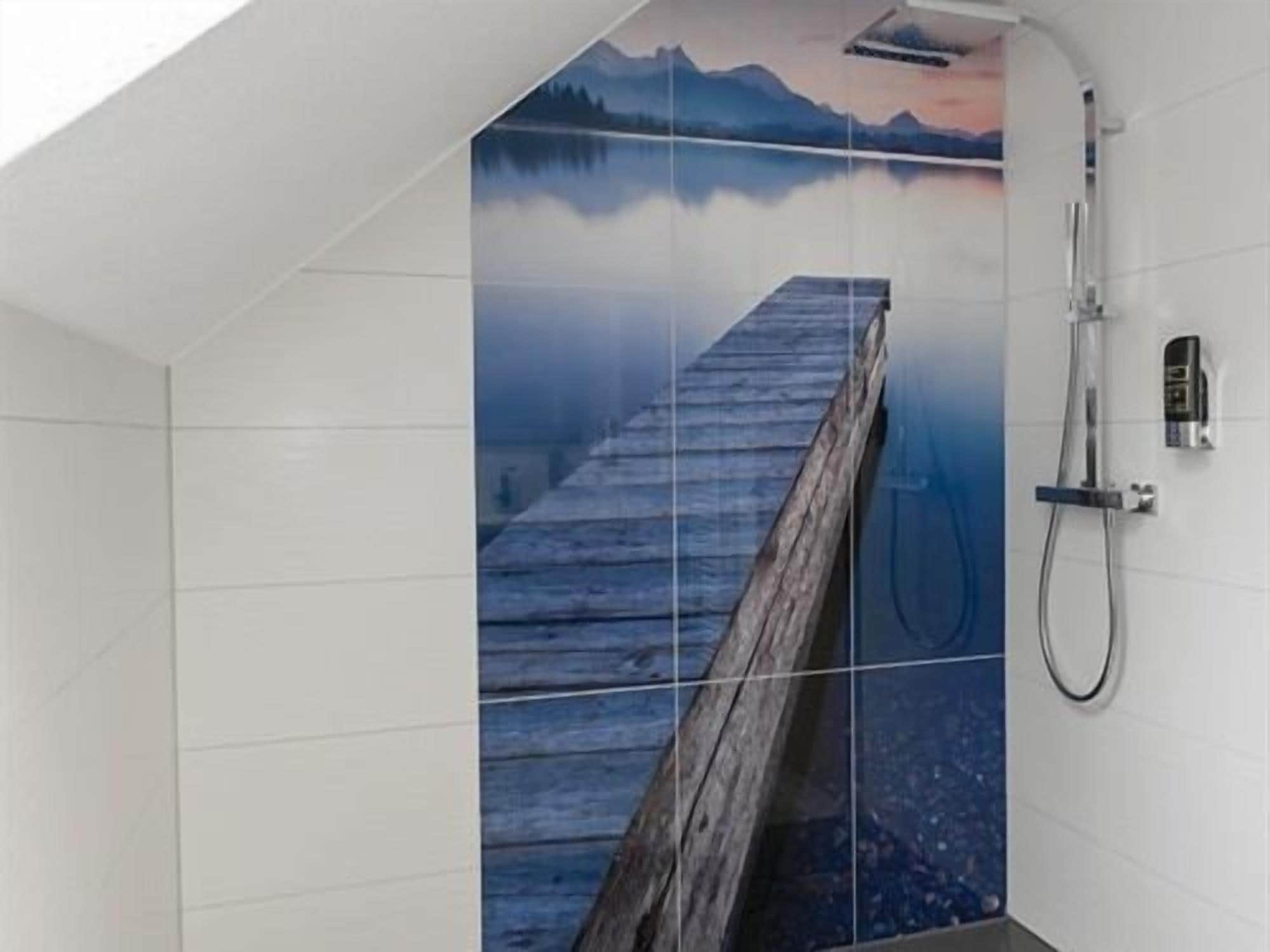 Une douche avec une plateforme en bois et une fresque murale représentant un paysage montagneux.
