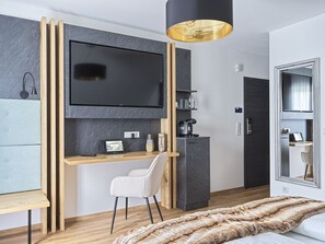 Une chambre moderne comprenant un lit, un bureau avec une chaise, une télévision, une machine à café et un miroir.