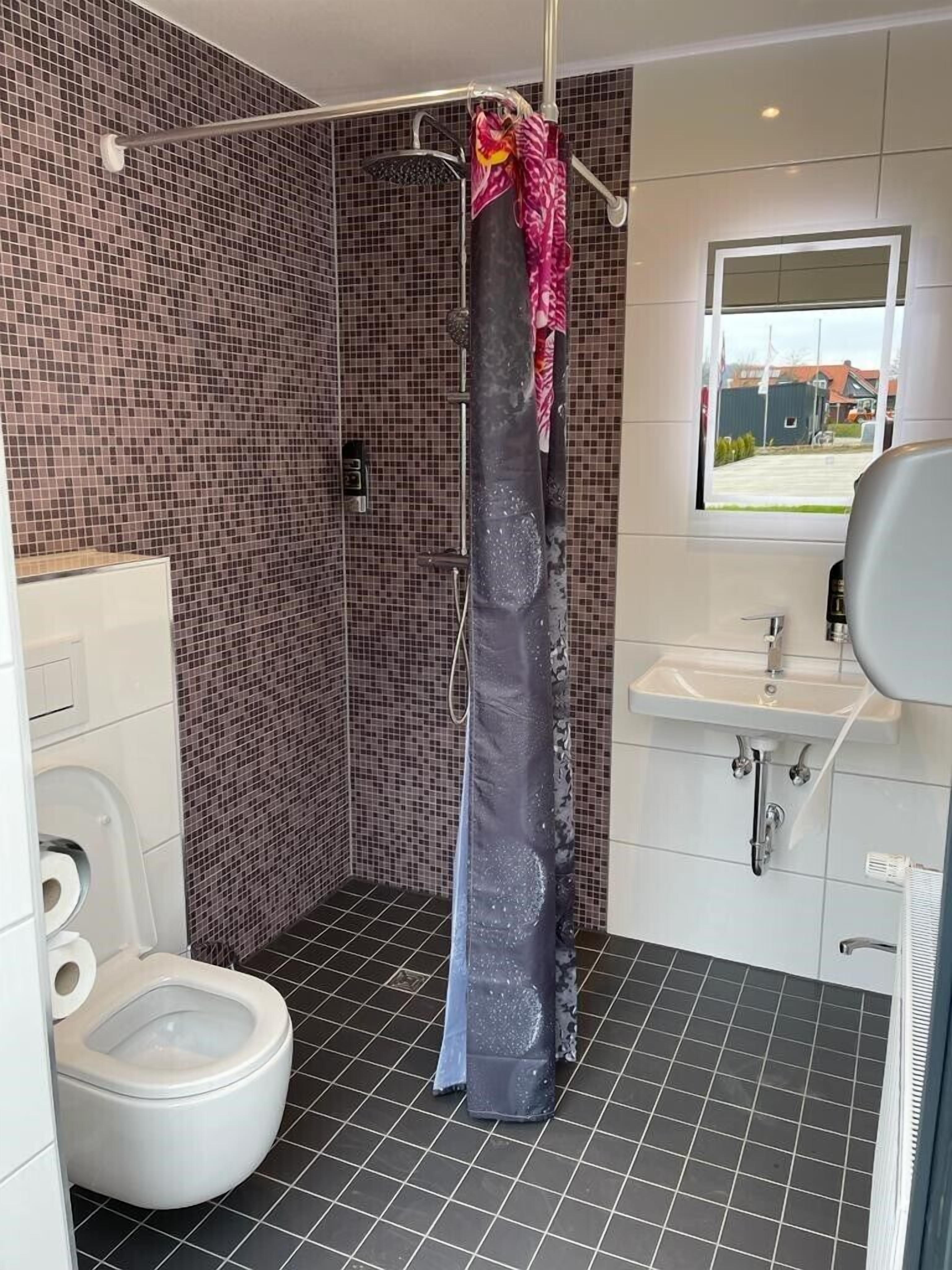 Ein Badezimmer mit Dusche, Toilette und Waschbecken.