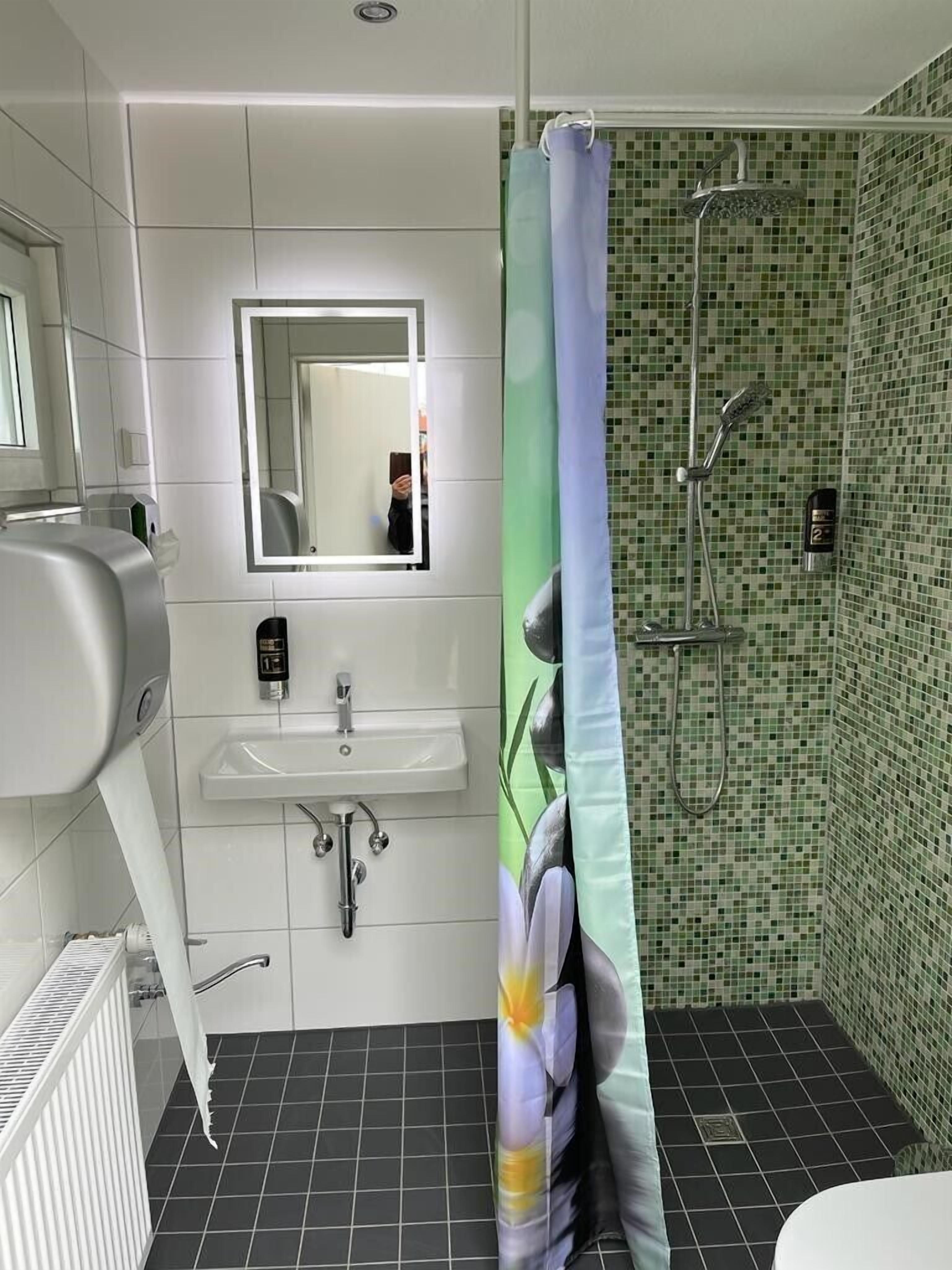 Ein modernes Badezimmer mit Waschbecken, Spiegel und Dusche.