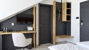 Ein modernes Schlafzimmer mit schrägverdeckter Decke, einem Schreibtisch mit Stuhl, einem Bett und einem Einbauschrank.