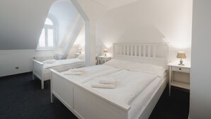A bedroom with two beds, white bedding, a radiator, and a window. - Penzion Dvorákova (Brno)