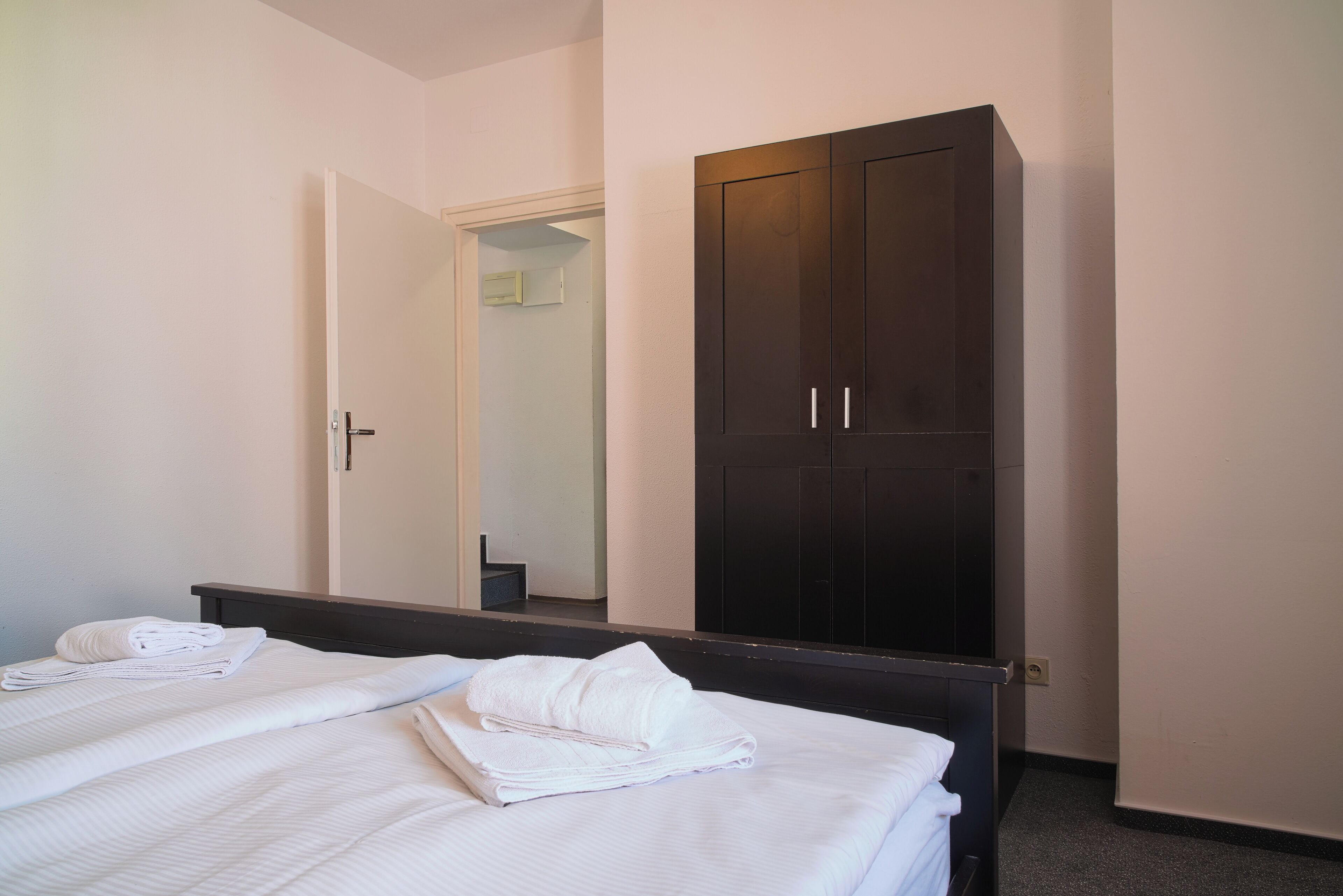 Une chambre d’hôtel avec un lit, une armoire et un miroir.