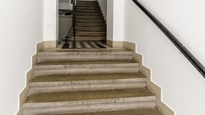 A staircase with a handrail, leading to an interior space with a window and a door. - Penzion Dvorákova (Brno)