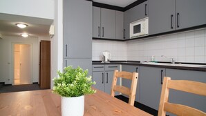 A modern kitchen with grey cabinets, a wooden dining table, and a potted plant. - Penzion Dvorákova (Brno)