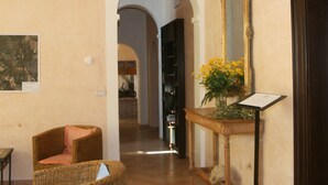 A hallway with a wicker chair, a mirror, and a vase of flowers. - Fattoria Nuova Pievanella (Civitella Paganico)