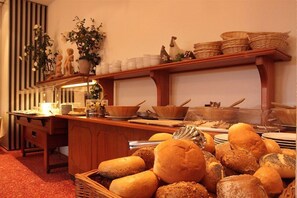 A buffet setup with bread, bowls, and decorative items on shelves. - Hotel Novum (Hinte)