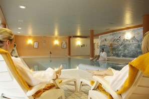 A pool area with lounge chairs and a mural of dolphins. - Hotel Novum (Hinte)