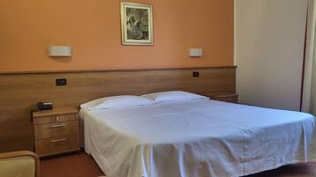 Ein Hotelzimmer mit einem Bett, einem Nachttisch aus Holz mit einem Telefon, einem Sessel und einem Gemälde an der Wand.