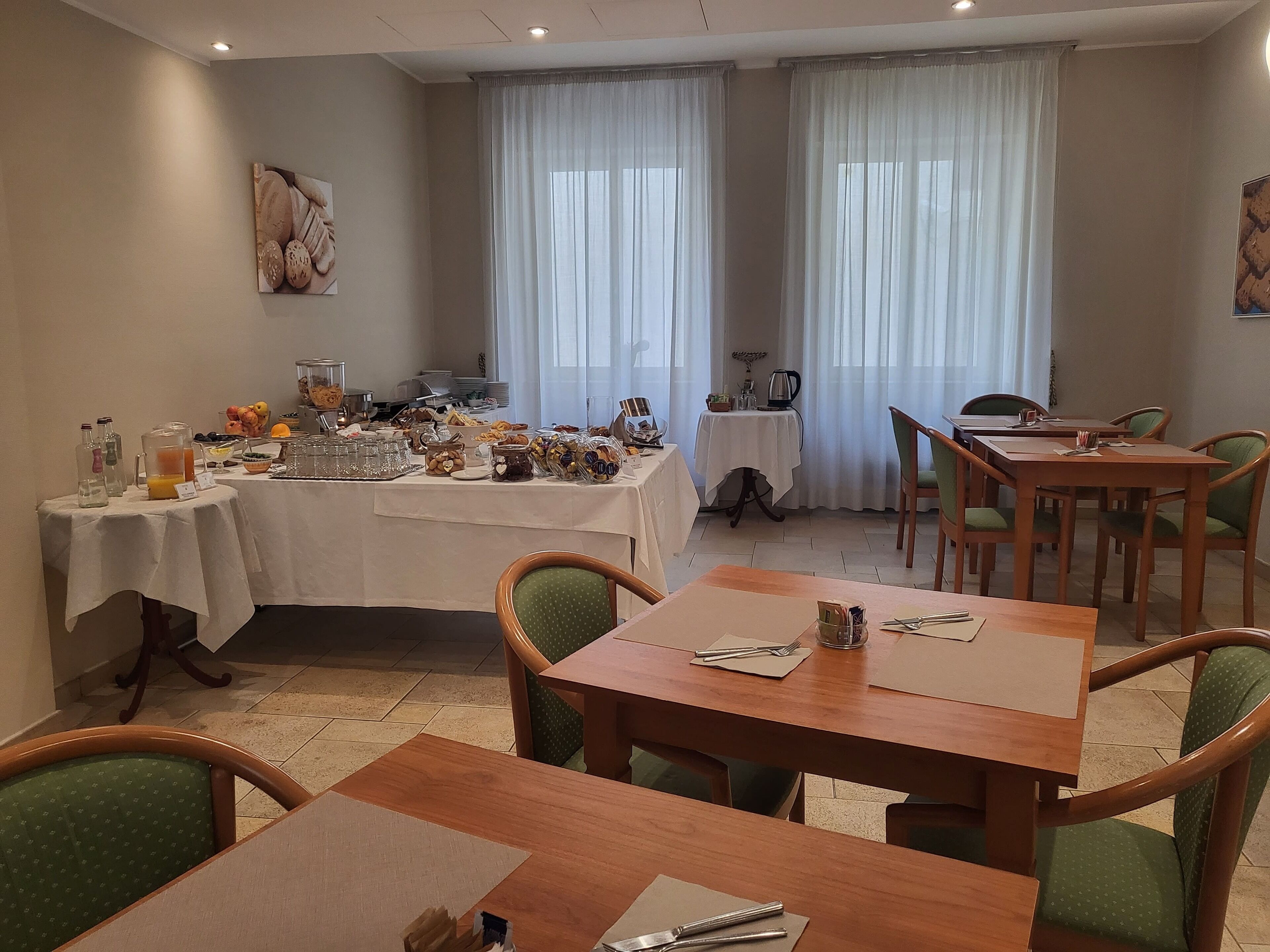 A dining area with tables and chairs, a buffet with various food items, and a coffee station.