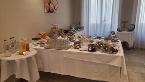 A breakfast buffet with various food items and beverages, a coffee machine, and a decorative wall piece. - Hotel Lux (Alessandria)