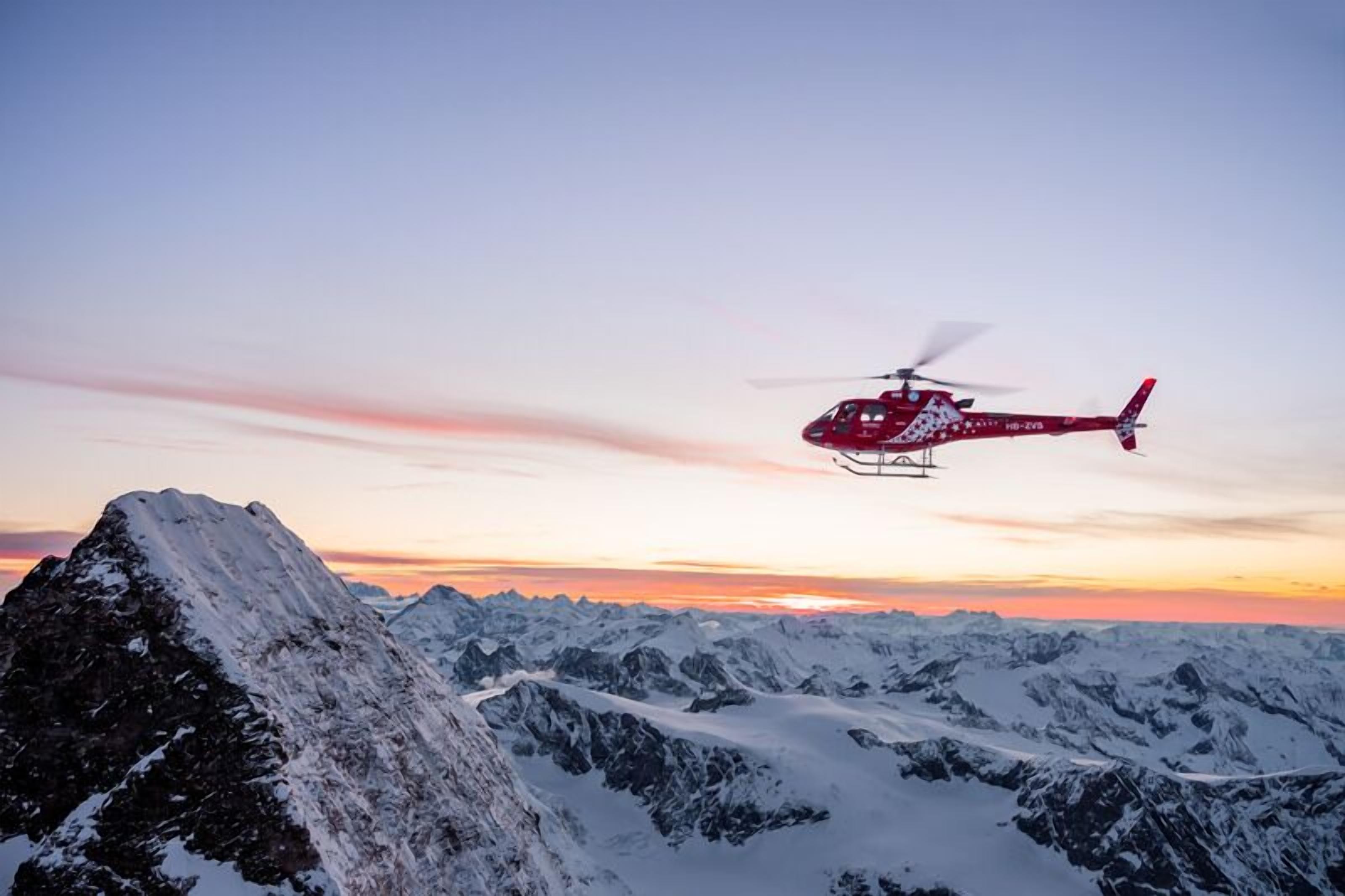 Ein Hubschrauber über einer verschneiten Berglandschaft.