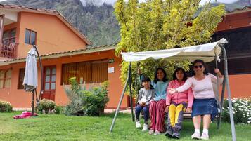A group of people sitting on a swing in a courtyard with a mountain backdrop.