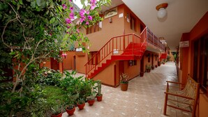 A hotel corridor with a red staircase, potted plants, and a bench. -  Hotel Lilium Valley Ollantaytambo (Ollantaytambo)